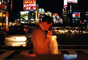 A Japanese businessman lights up a cigarette in neon streets of Shinjuku, Tokyo.