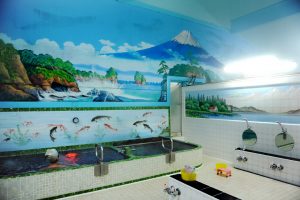 A Japanese woman in a public bath, sento, with the wall painted of Mt. Fuji in Tokyo.