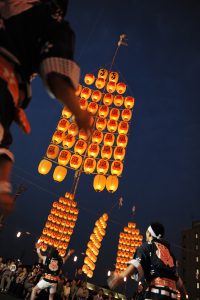A man holds lantern pole on his forehead at Kato Festival in Akita.