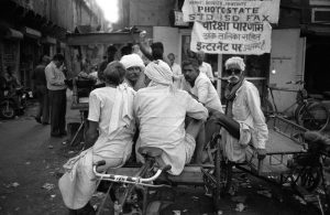 Drivers of rickshaw rest and chat on a street in Delhi, India.