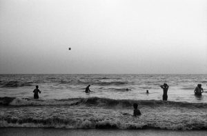 Indian people play wtih a ball in the ocean in Mumbai.