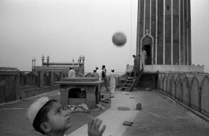 Indian muslim boy play with a ball on the roof of Jama Masjid, the biggest mosque in Delhi.