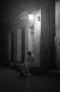 A man sits under the street light in Stone Town, Zanzibar, Tanzania.