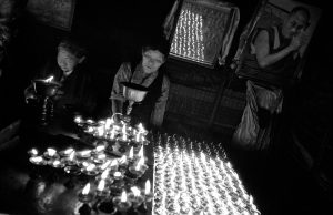 Tibetans pilgrims light up candles in the Bodhnath stupa with the portrait of Dalai Lama, Nepal
