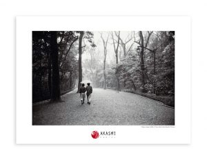 A Japanese couple walks under an umbrella on a path in Meiji Jingu Shrine.